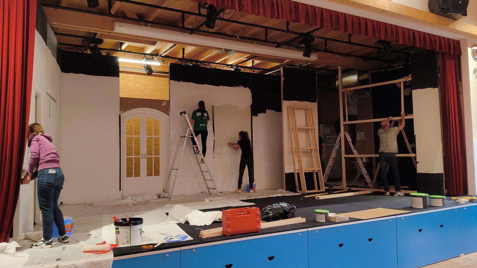 Montage du décor sur la scène de la salle communale : peinture des panneaux et assemblage des cadres en bois