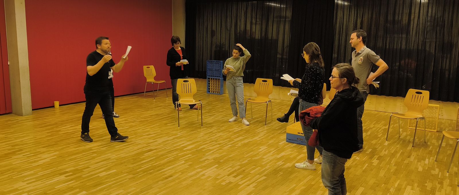 Répétition à la salle : le metteur en scène explique une scène aux comédiens, textes en main